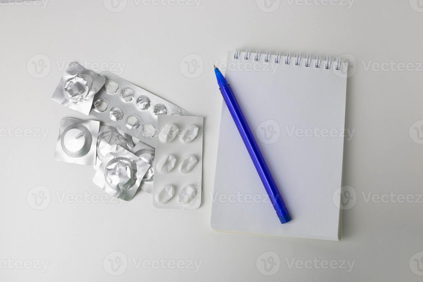 Empty blisters, a notebook and a pen are on the table photo