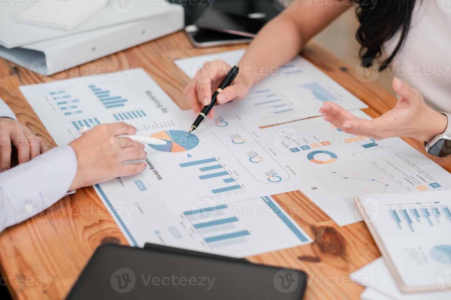 Close-up of hands pointing at financial charts and graphs during a business meeting for strategic planning. photo