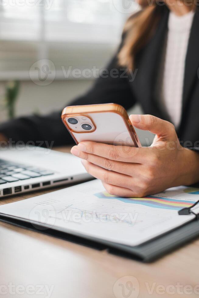 Close-up of a business professional using a smartphone and laptop, highlighting modern work and communication. photo