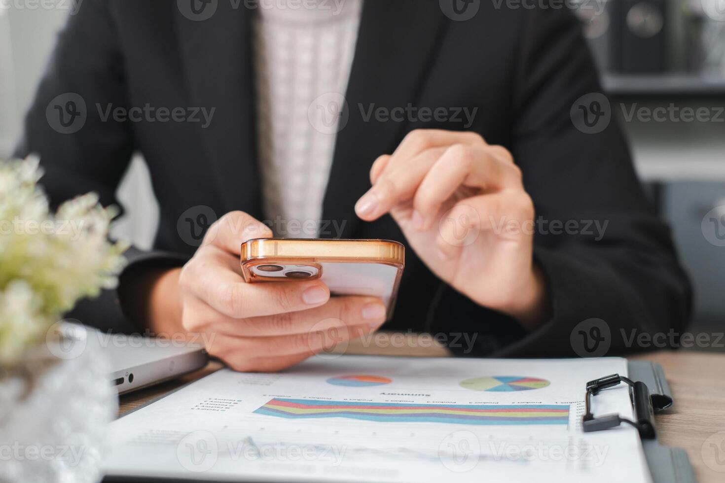 Businessperson using smartphone to review financial charts and graphs in a modern office environment. photo