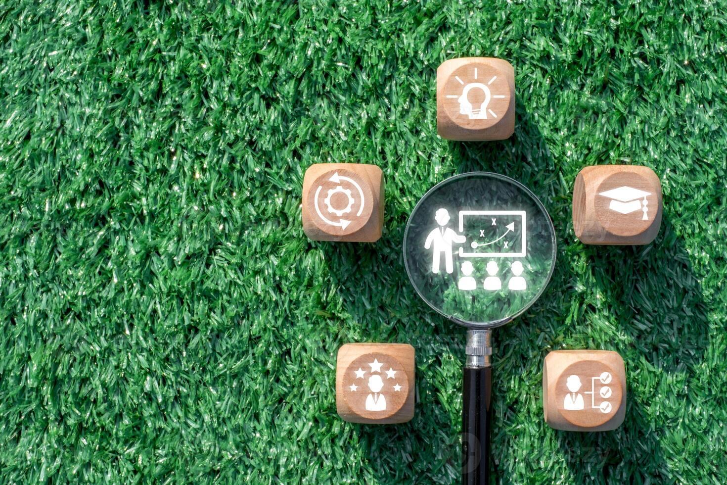 Innovative Training Concept with Magnifying Glass and Wooden Blocks on Green Grass Background photo
