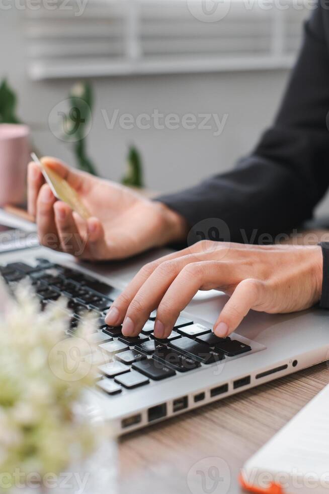 Close-up of Hands Using Laptop for Online Shopping with Credit Card in Modern Office Setting photo