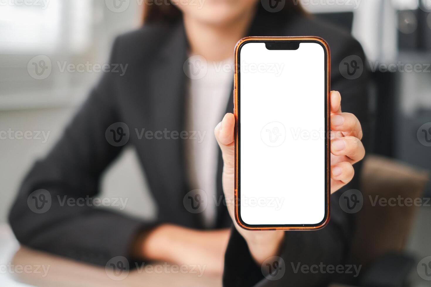 Professional woman in a suit holding a smartphone with a blank screen, ideal for app or website mockups. photo