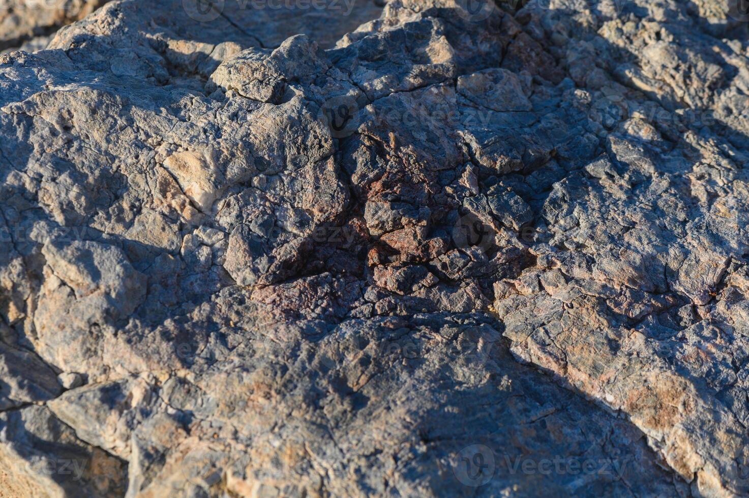 Close-up view of textured rock formations under warm sunlight on a tranquil outdoor setting. photo