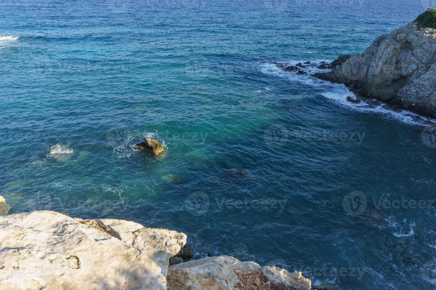 Crystal clear waters gently lapping against rocky shores at daylight in a serene coastal landscape. photo