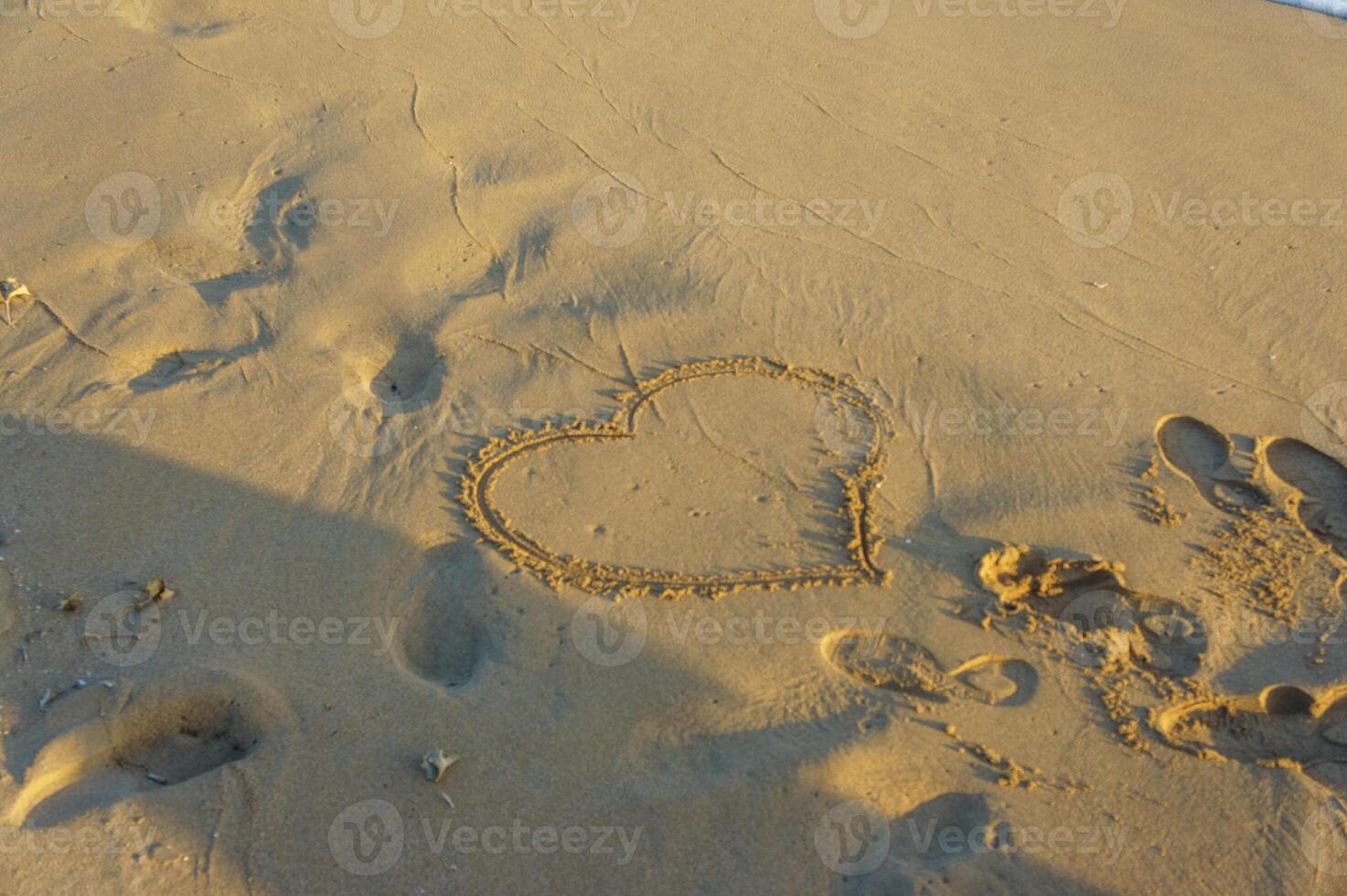 A romantic heart drawn in the sand at sunset on a tranquil beach getaway. photo