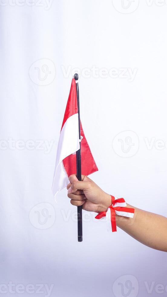 Man's Hand is Holding Red and White Indonesian Flag to Celebrate Independence Day of Indonesia Isolated on White Background photo