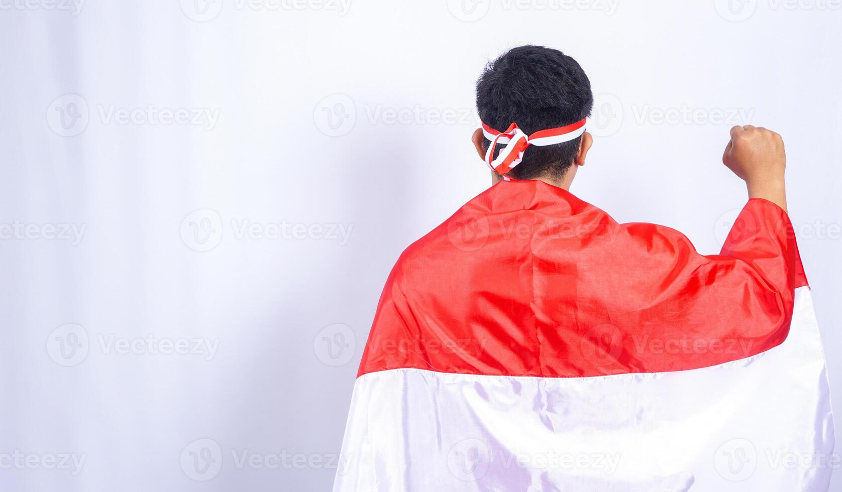 Back Portrait of Indonesian Young Man with Country Flag Draped over His Shoulders photo