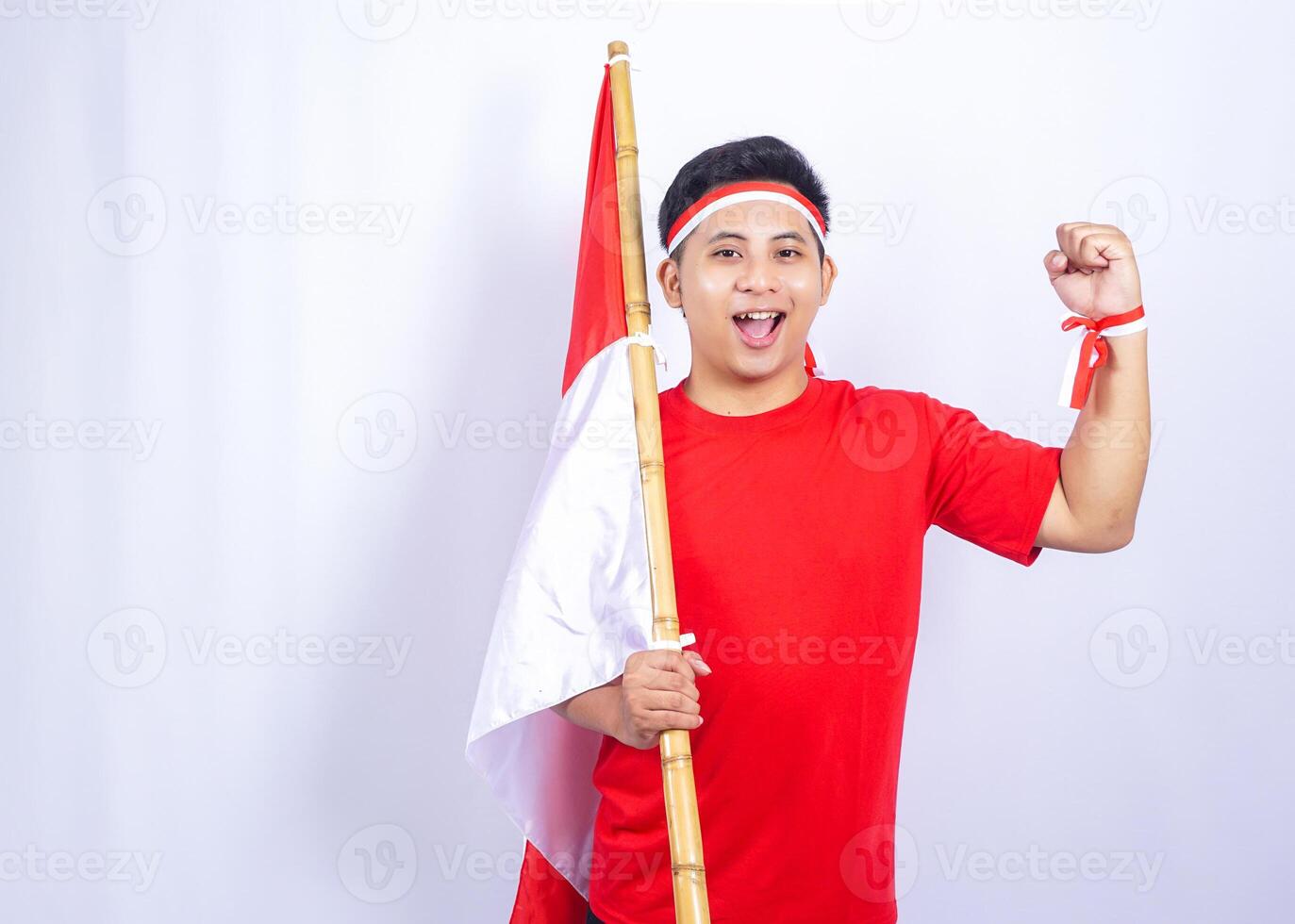 Excited Indonesian Young Man Holding Red and White Indonesia National Flag while Raising Fist photo