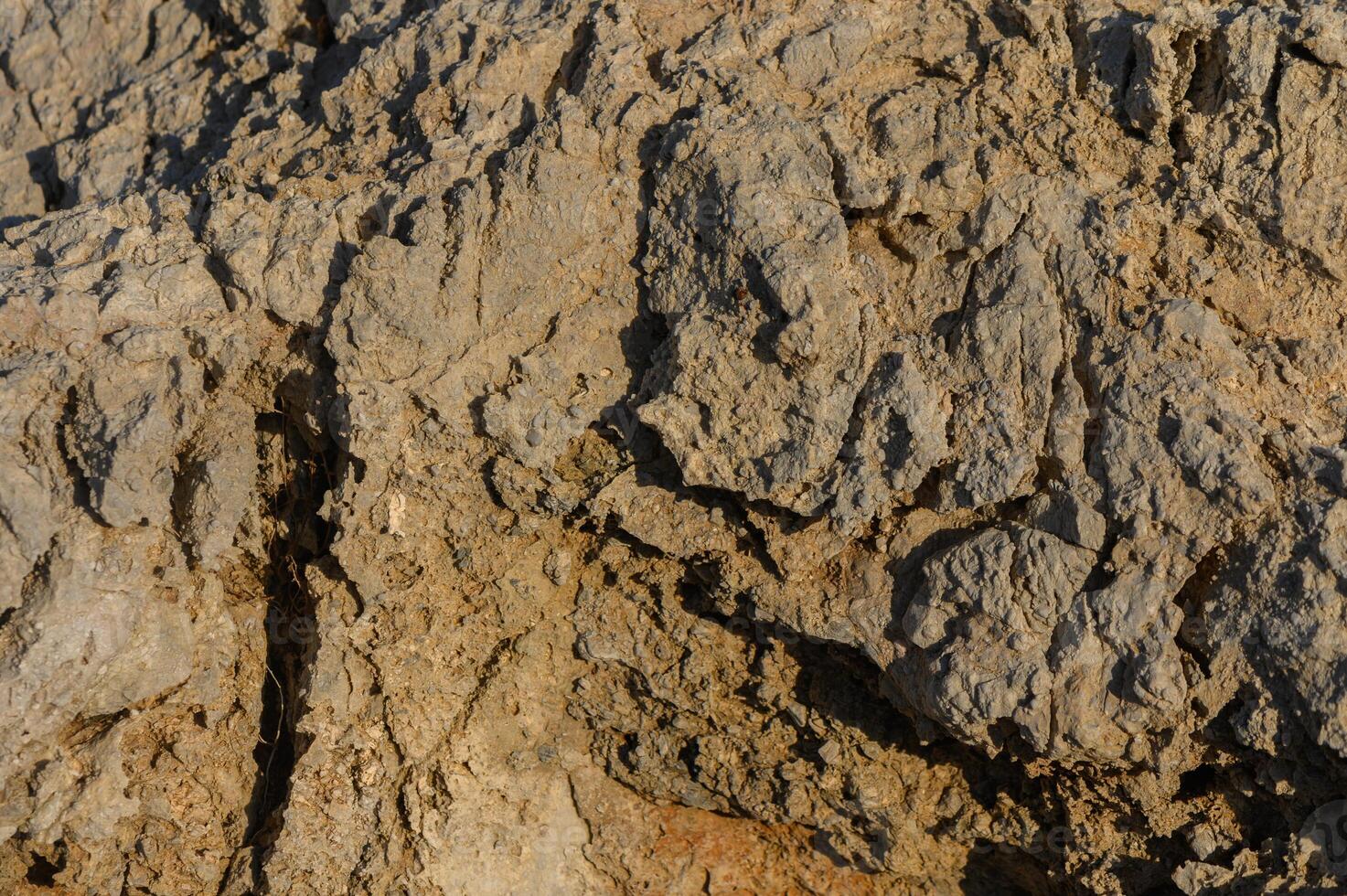 Textures of weathered rock formation illuminated by warm sunlight at the edge of a rugged landscape. photo