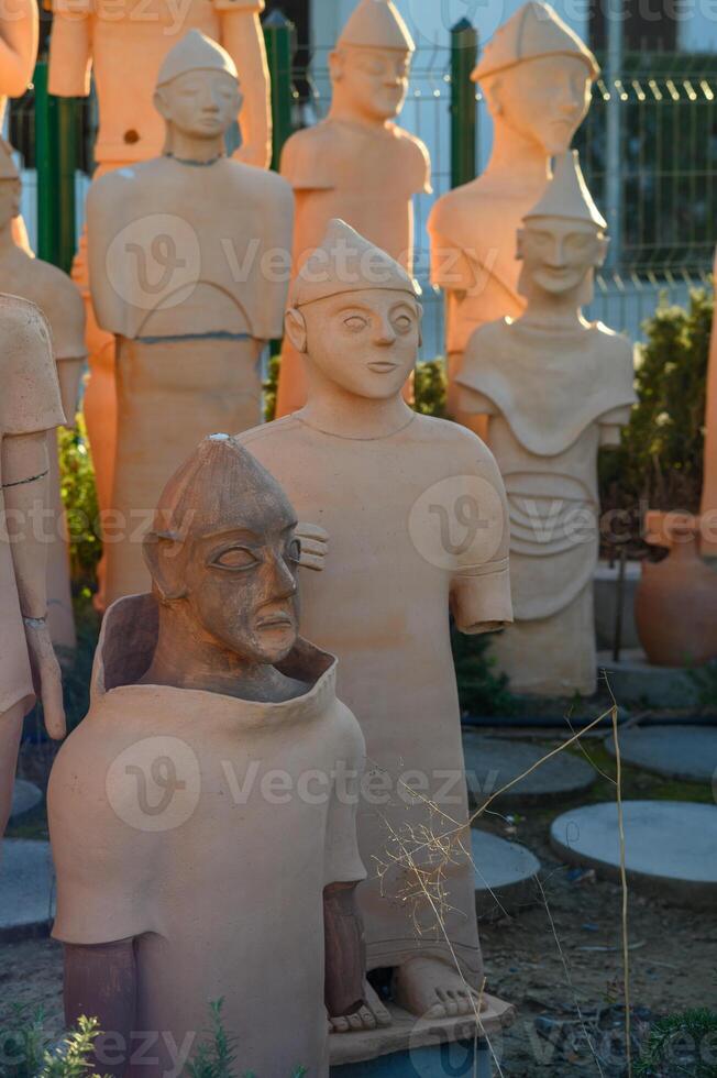 Unique collection of ancient terracotta figures displayed in an outdoor museum at sunset photo