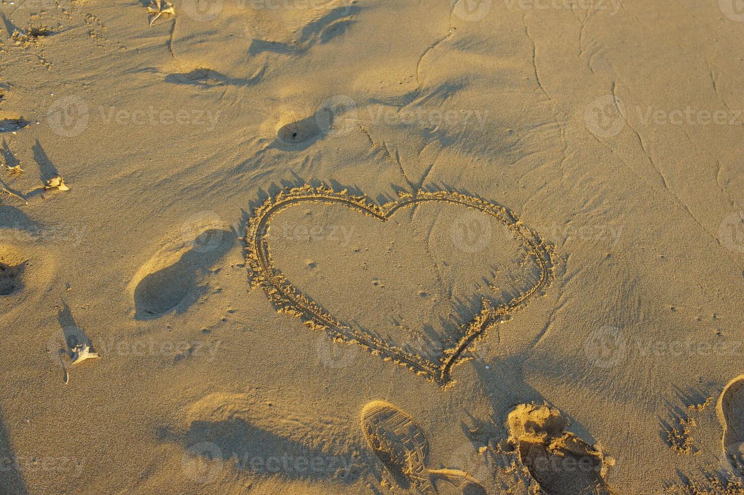 A heart drawn in the sandy beach at sunset, capturing a moment of love and tranquility by the ocean. photo