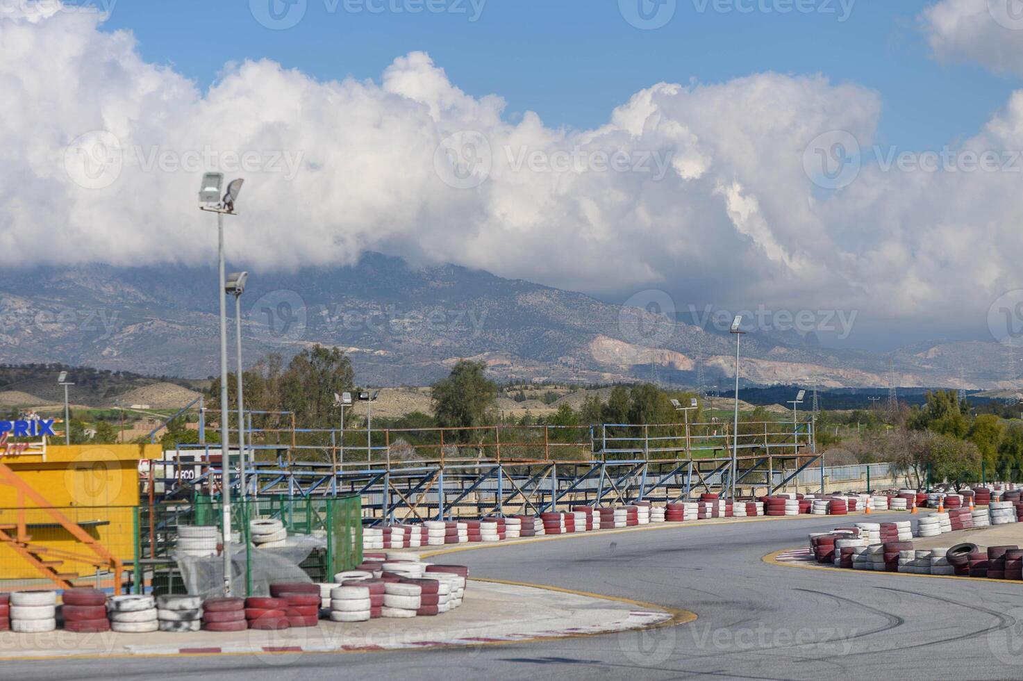 Race track under clouds with scenic mountains in background during a bright day photo