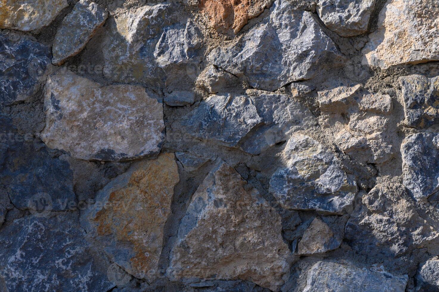 Textured stone wall showcasing natural hues and rugged beauty in sunlight on a serene day photo
