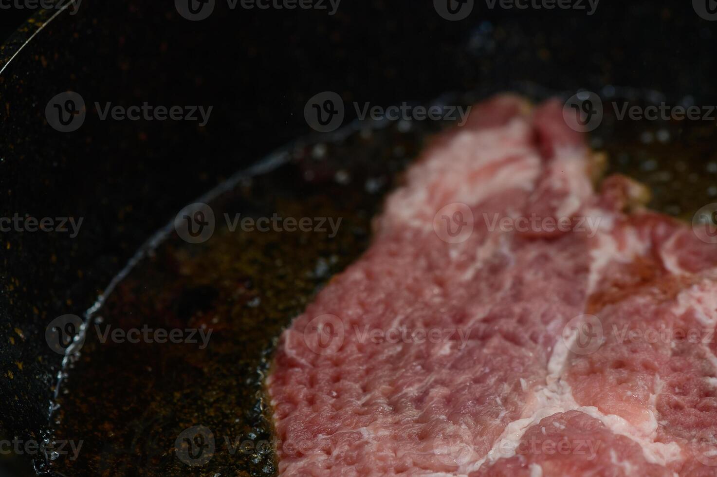 Sizzling pork steak cooking in a cast iron skillet on a rustic kitchen stove photo