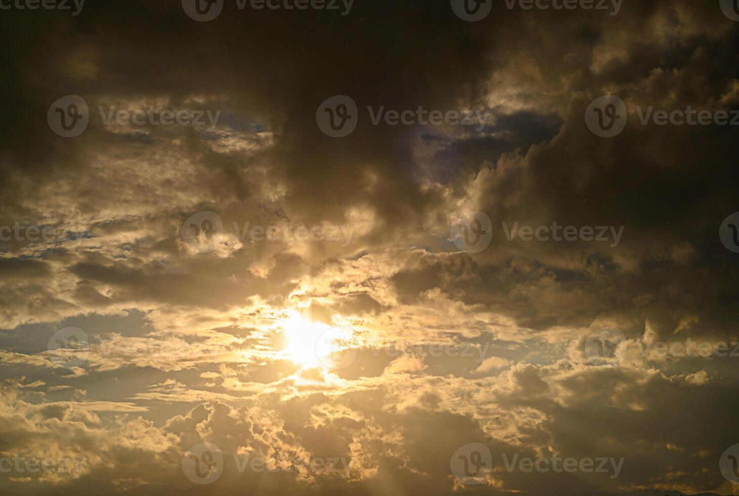 Golden rays pierce through dramatic clouds during a tranquil sunset sky photo