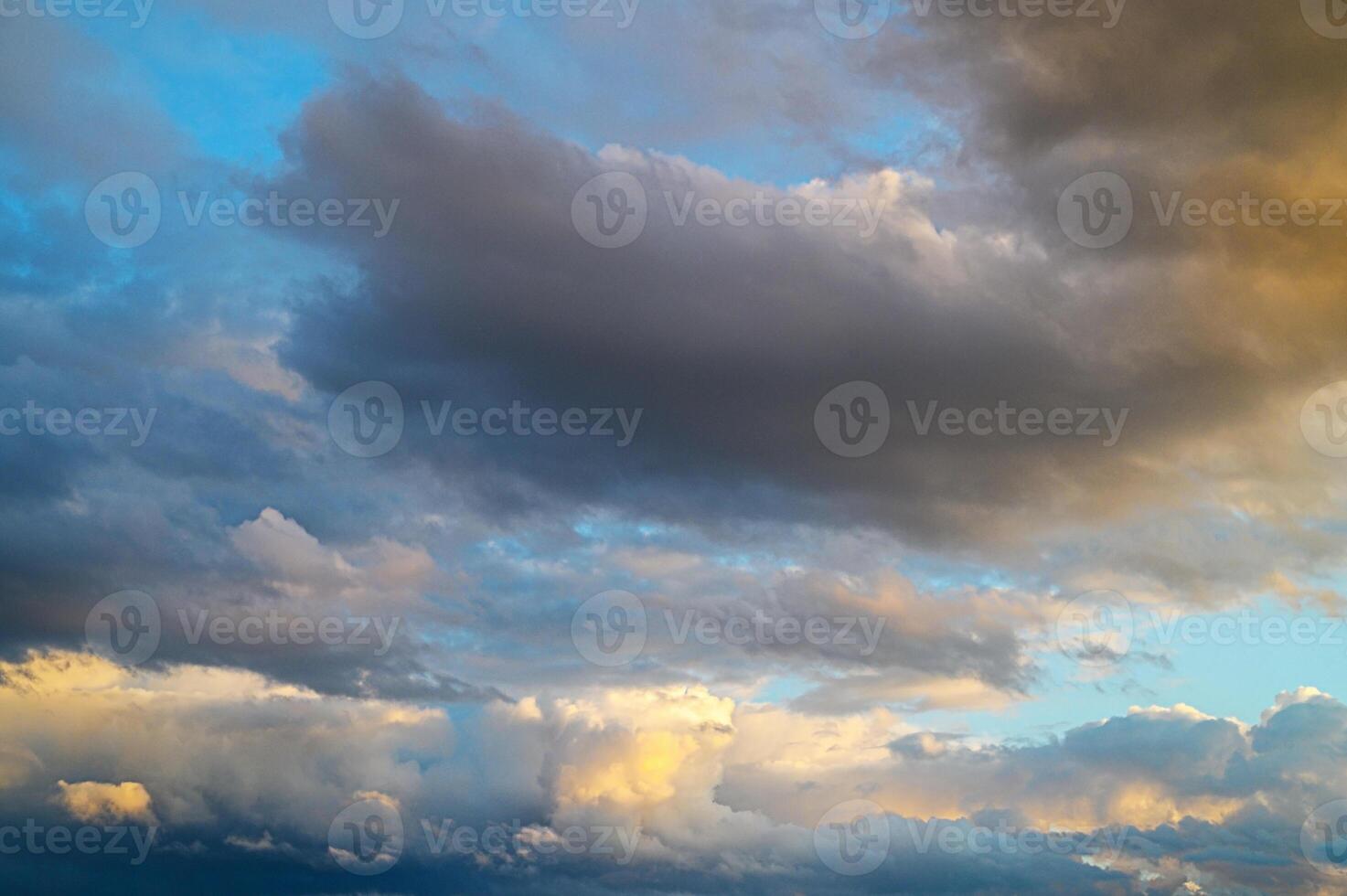 Shifting clouds dance across the vibrant sky at sunset, painting the horizon with golden hues photo