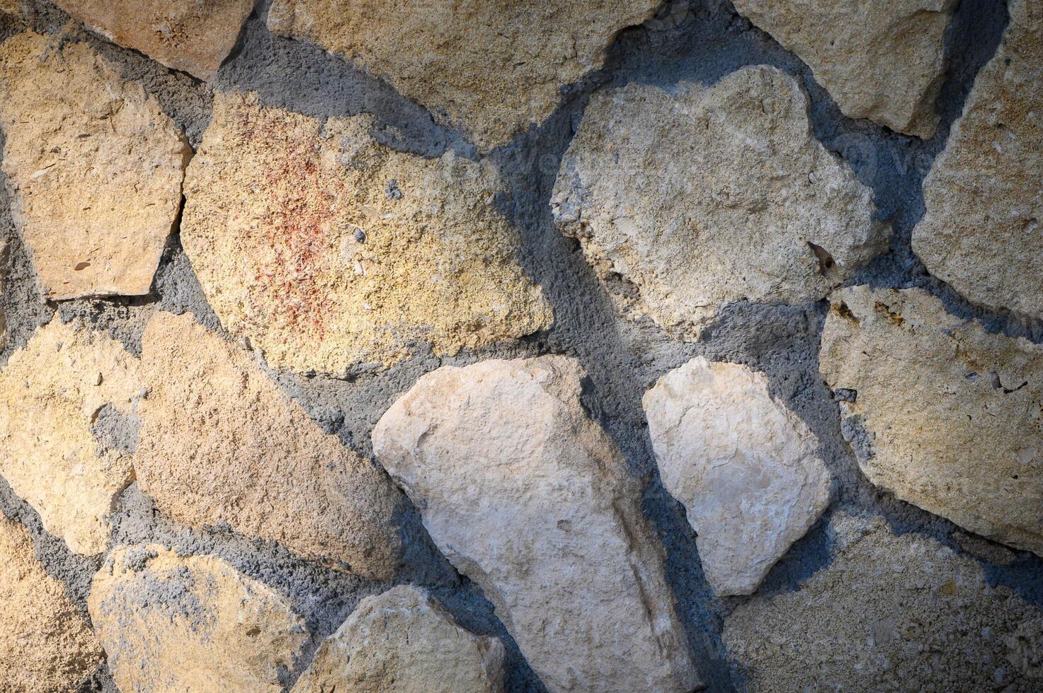 Rustic stone wall showcases natural textures and earthy tones in warm sunlight photo