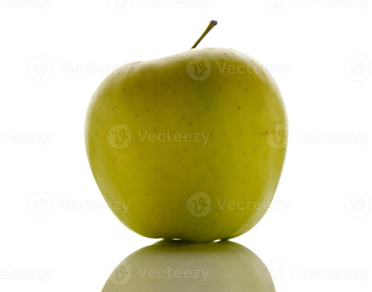 Vibrant green apple standing on a reflective surface under bright light creating a striking visual contrast photo