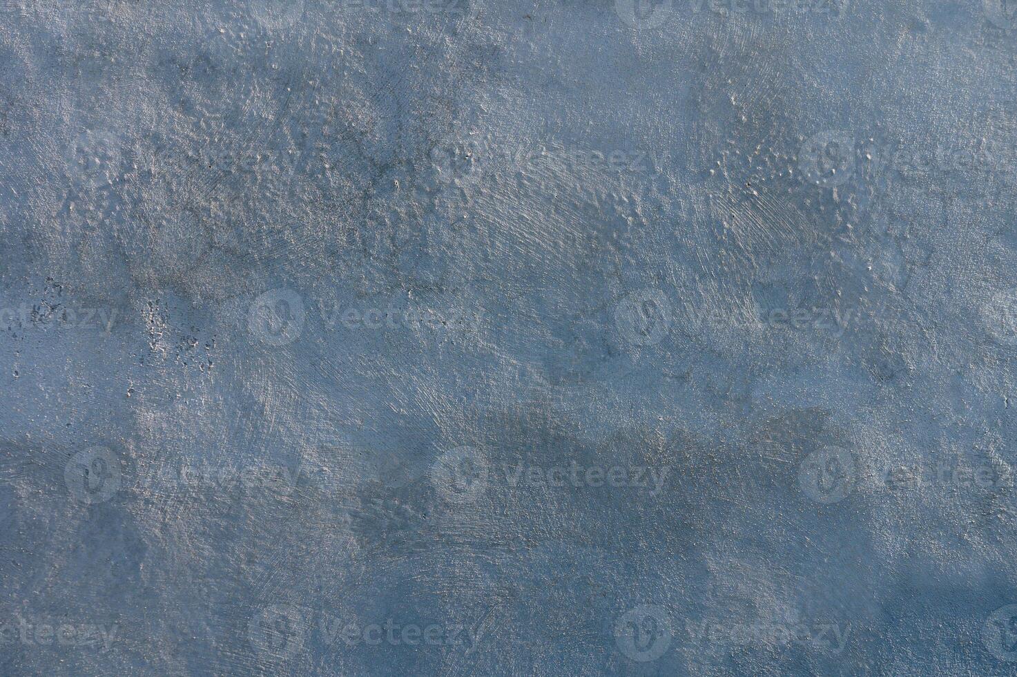 Swirling shades of blue grace the textured surface of a tranquil water body under soft sunlight photo
