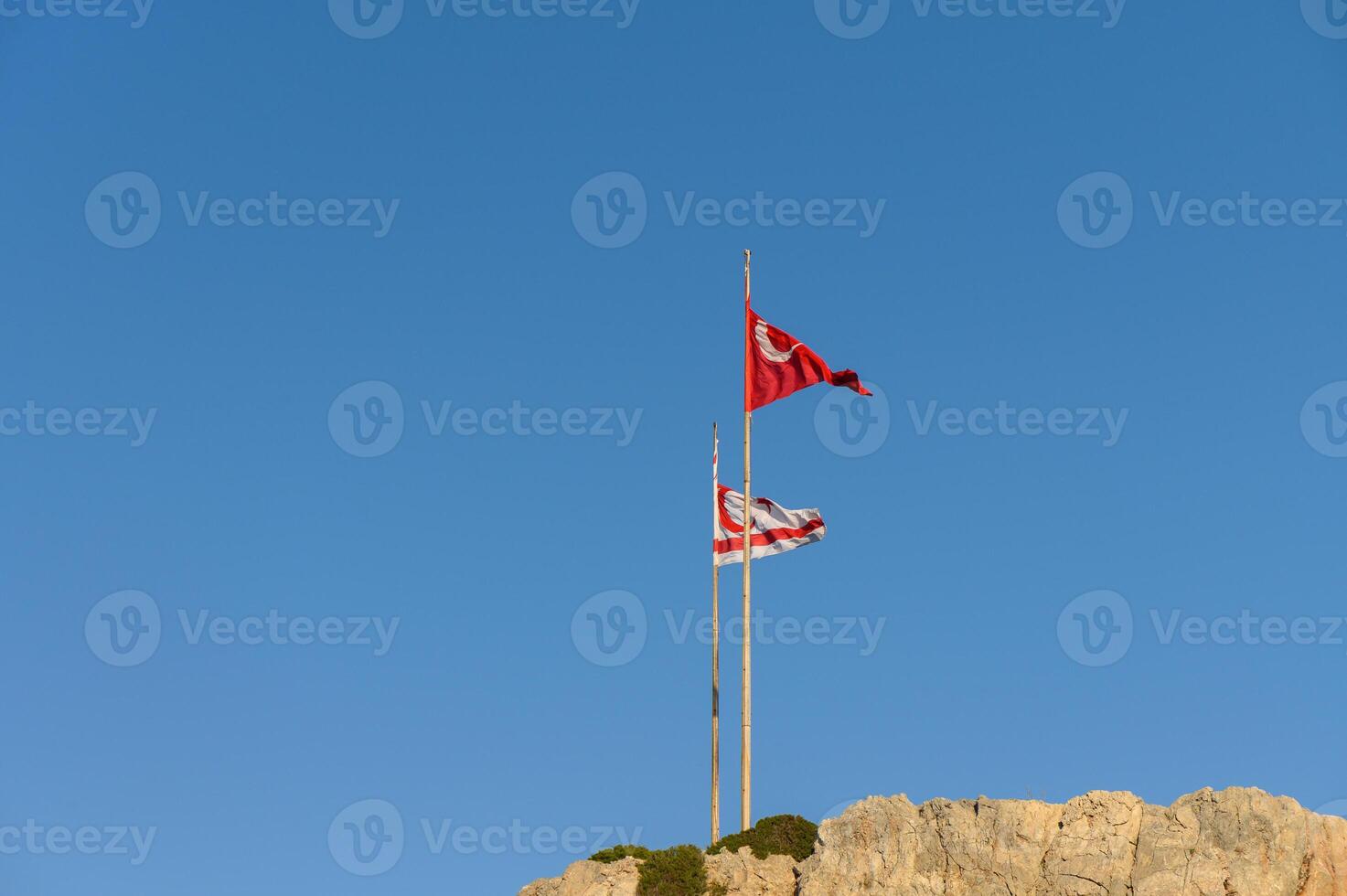 Flags of Tunisia and the local community wave proudly against a clear blue sky at sunset. photo