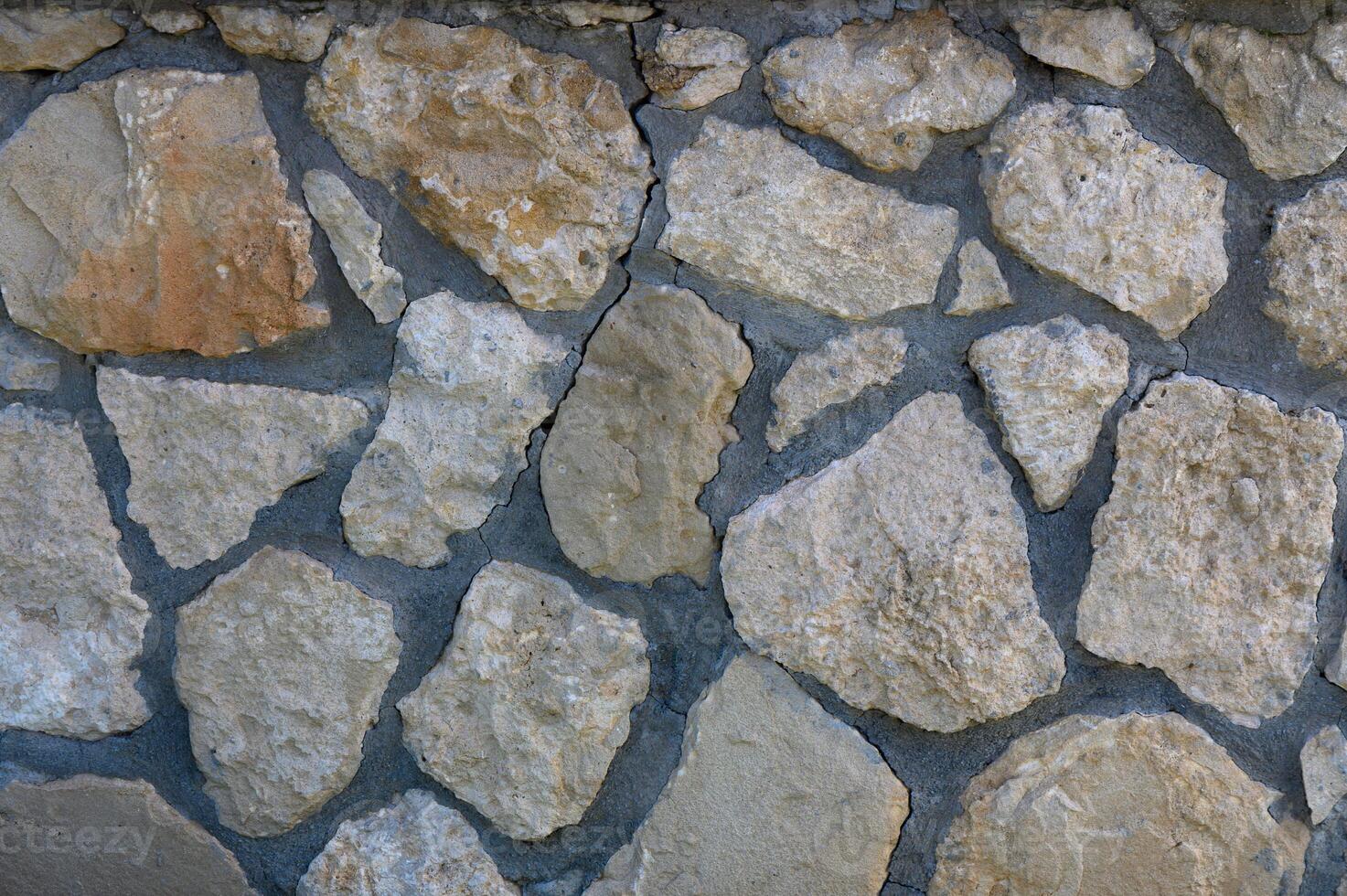 Textured stone wall showcasing natural patterns and earthy tones in sunlight photo