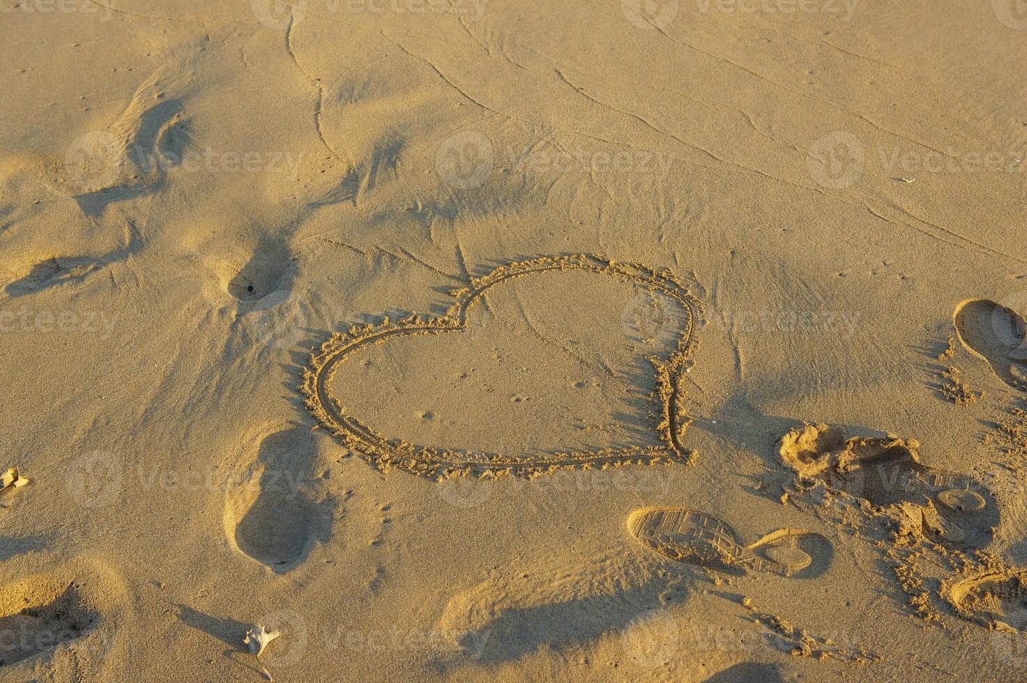 A heart drawn in soft sand on a sunlit beach, capturing lo photo
