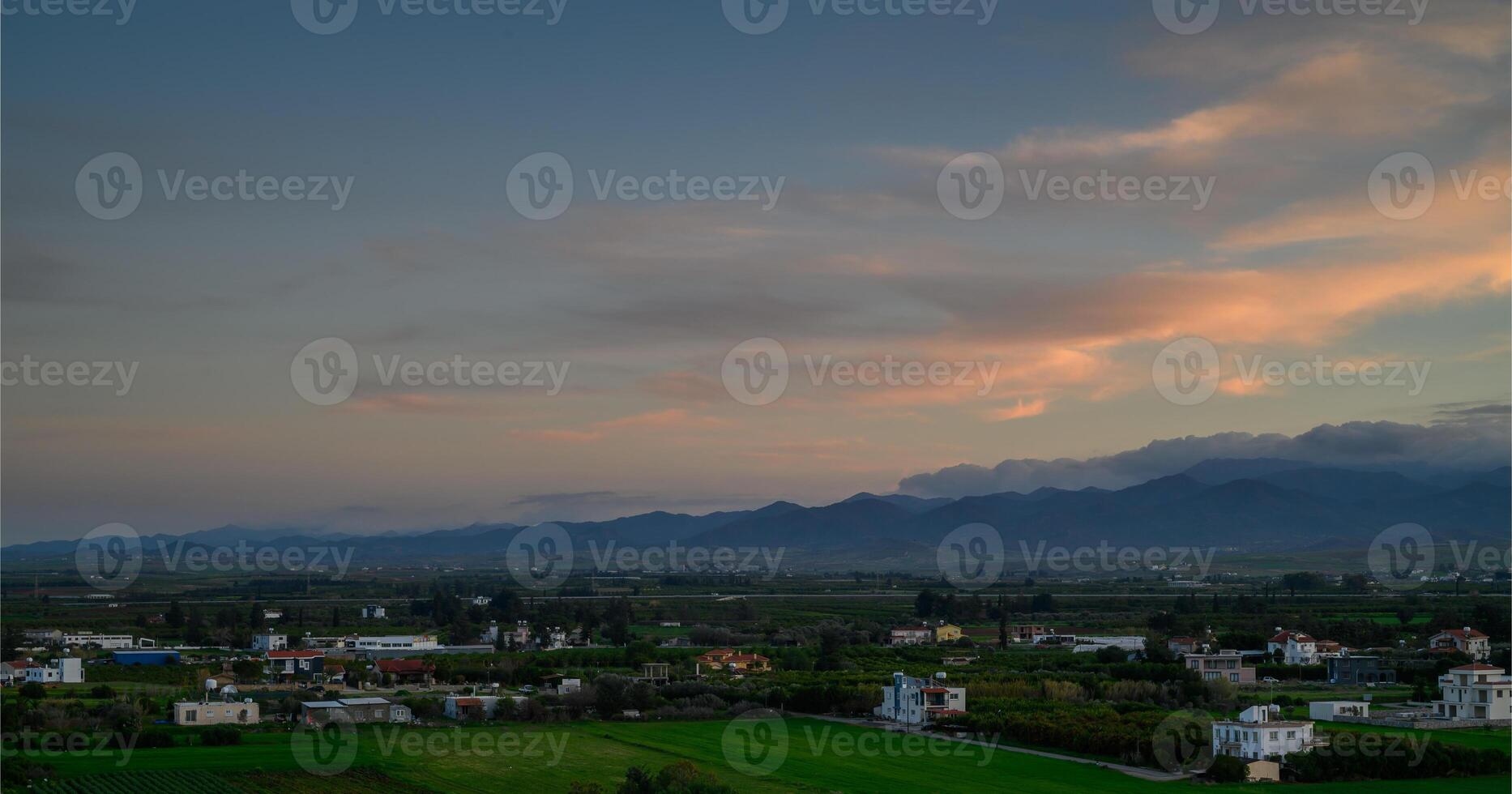 Sunset over serene countryside landscape with mountains and fields in the distance photo