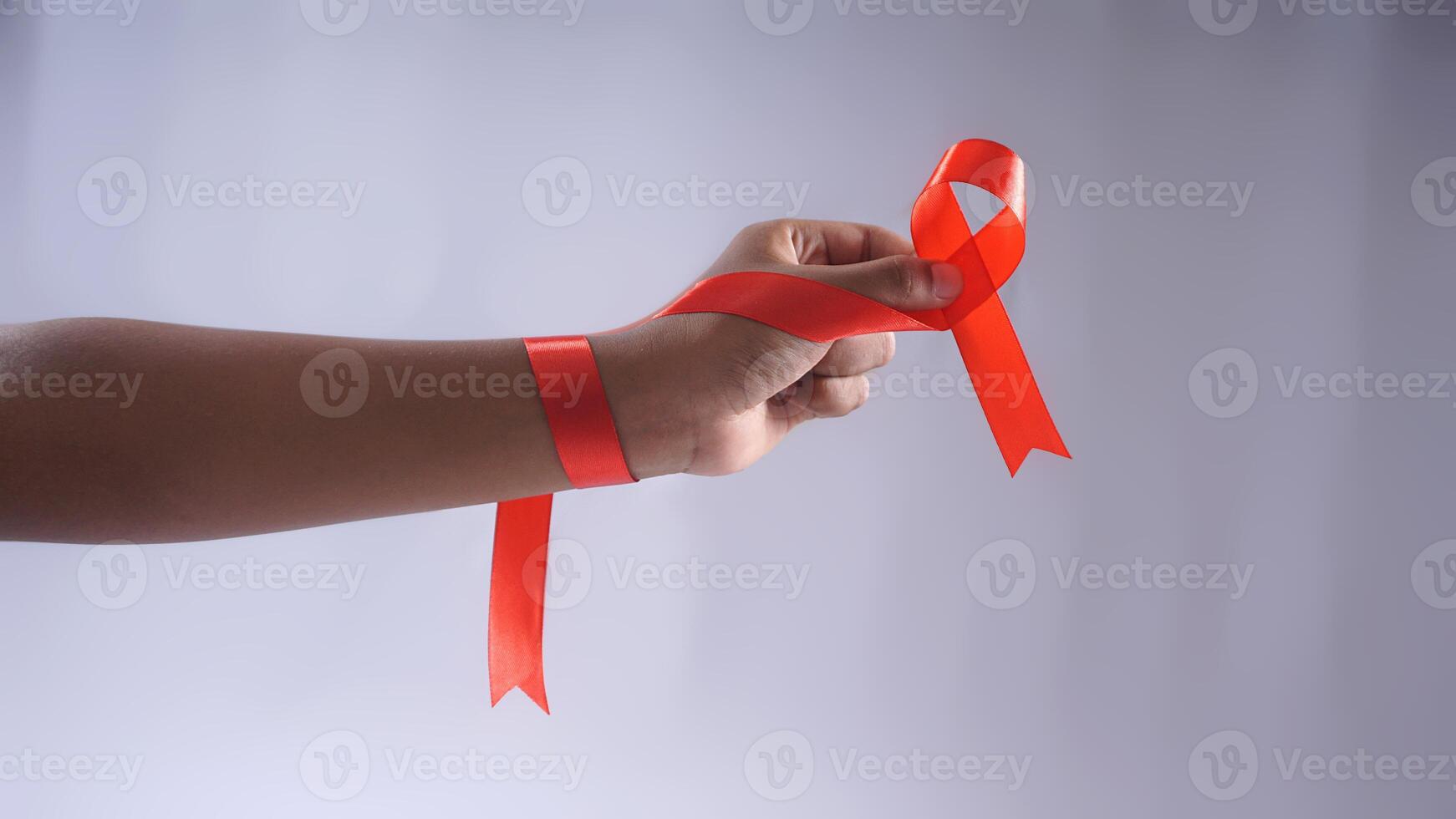 Hand Holding Red Ribbon Symbol of HIV AIDS Awareness photo