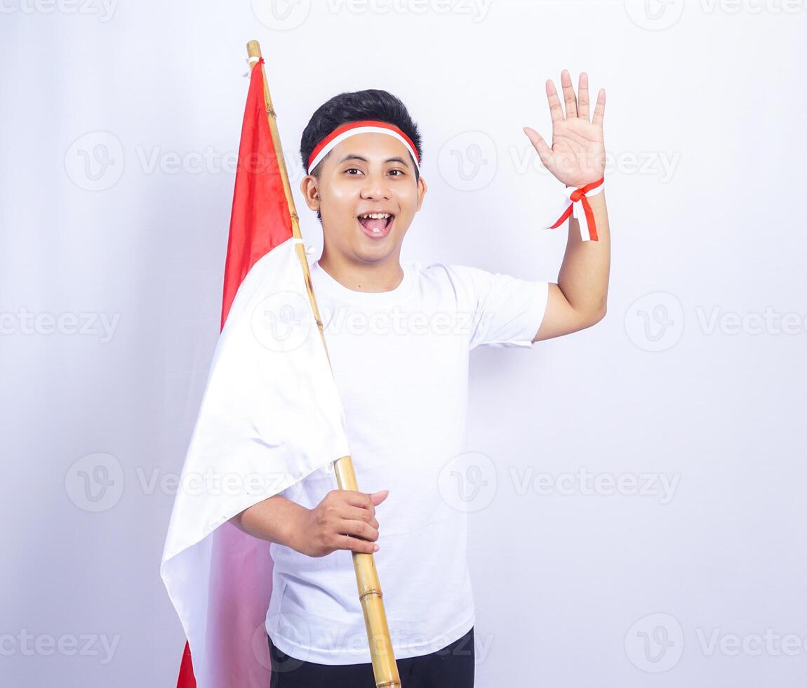 Indonesian Young Man Gesturing Hello to Greets People with Hand while Holding Country Flag photo