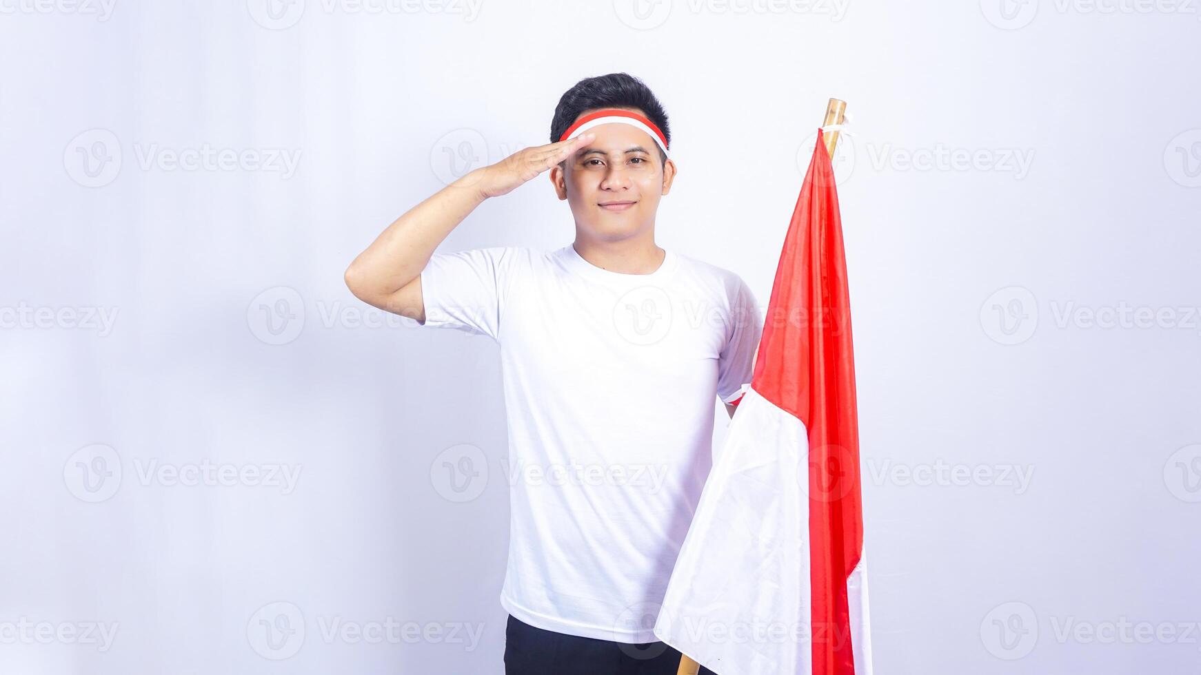 Indonesian Young Man Giving Salute while Holding Country Flag photo