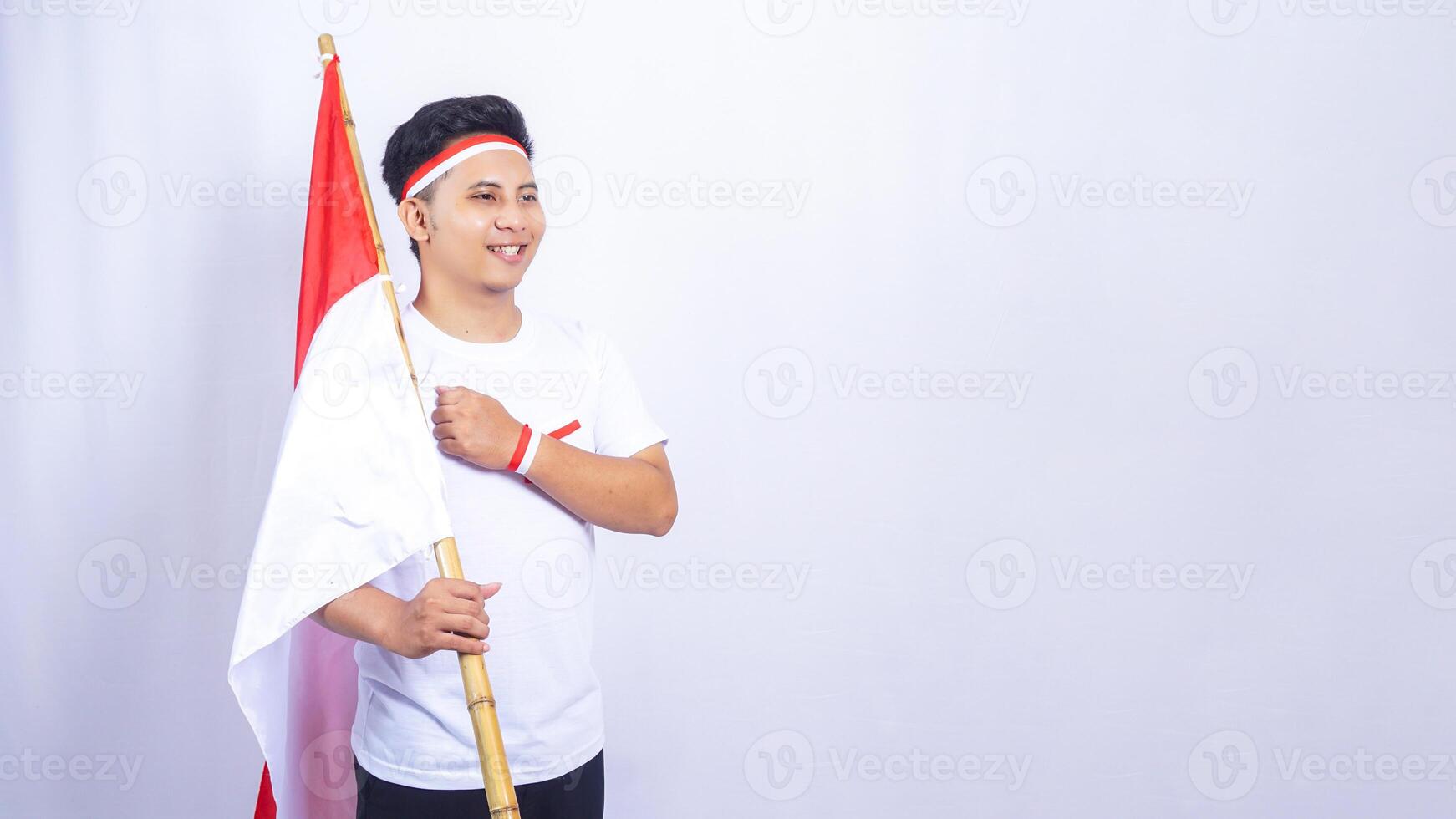 Indonesian Young Man Raising Fist in front of His Chest while Holding Country Flag Isolated on White Background photo