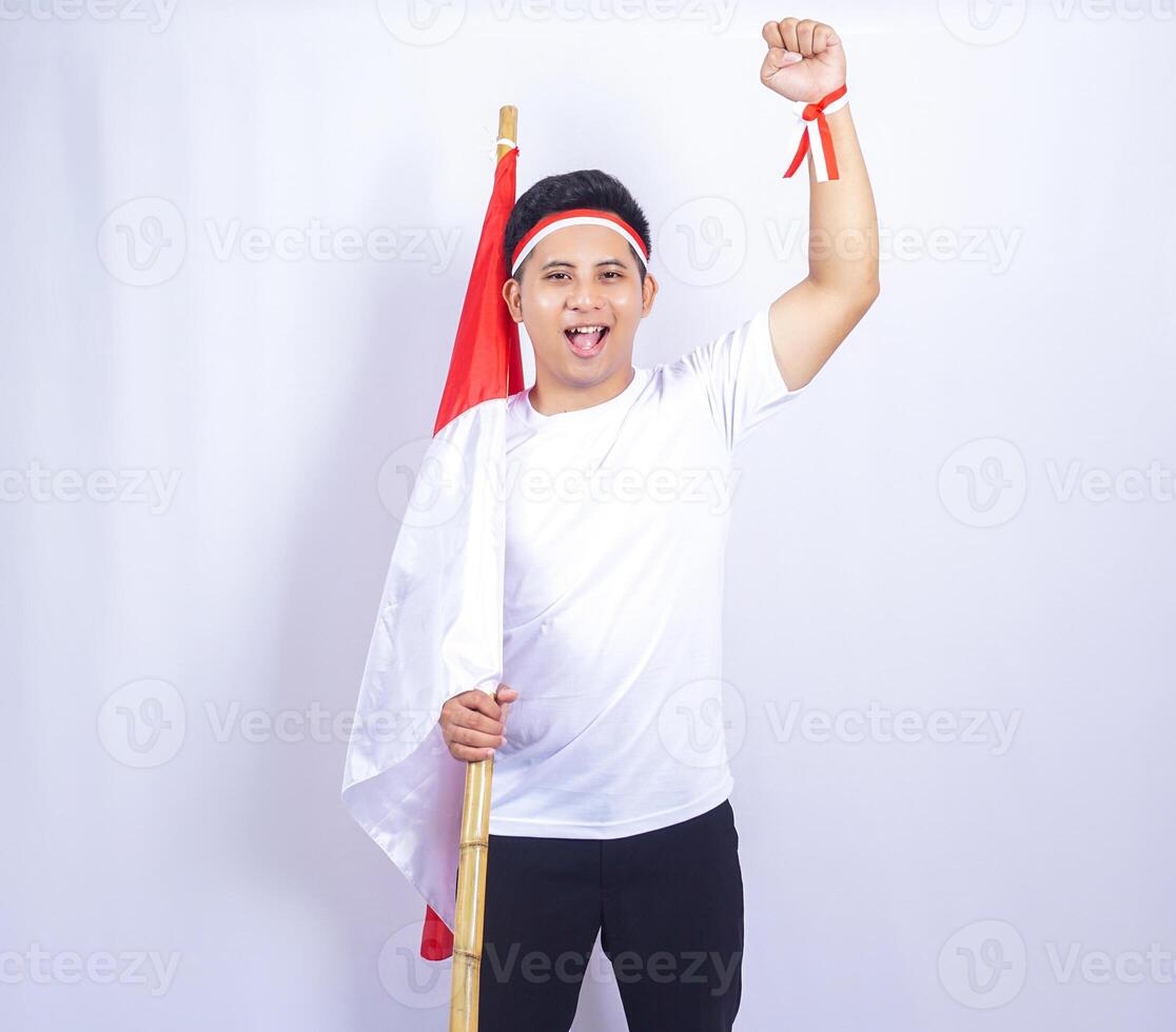 Overjoyed Indonesian Young Man Raising Fist while Holding Country Flag photo