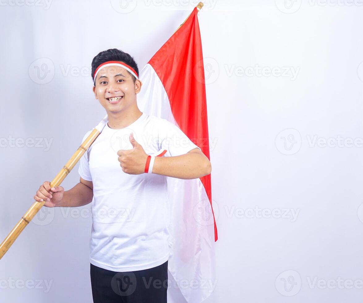 Excited Indonesian Young Man Showing Thumbs up while Holding Country Flag photo