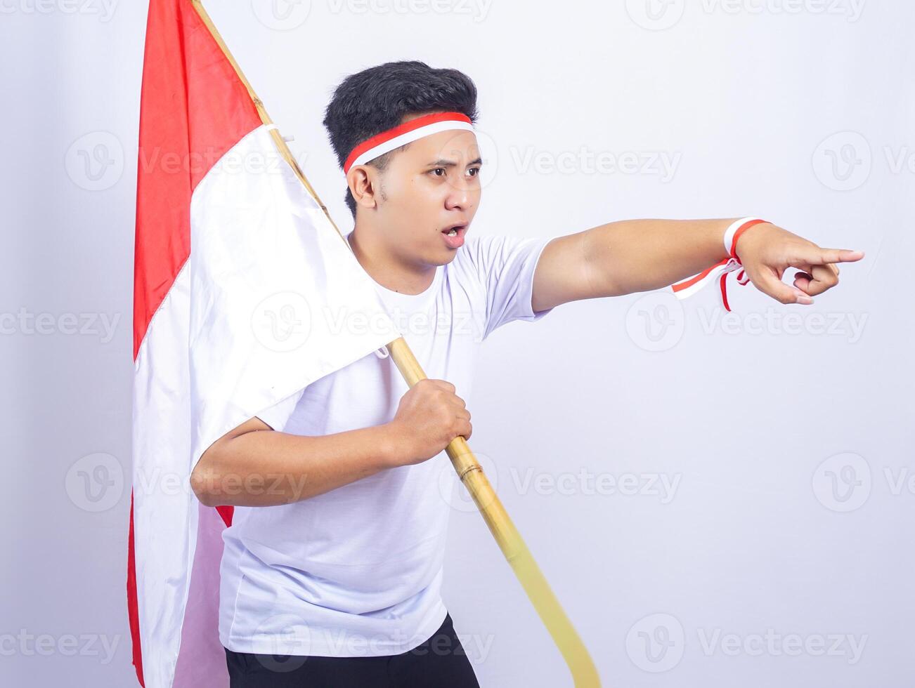 Indonesian Young Man Holding Country Flag with Serious Facial Expression photo