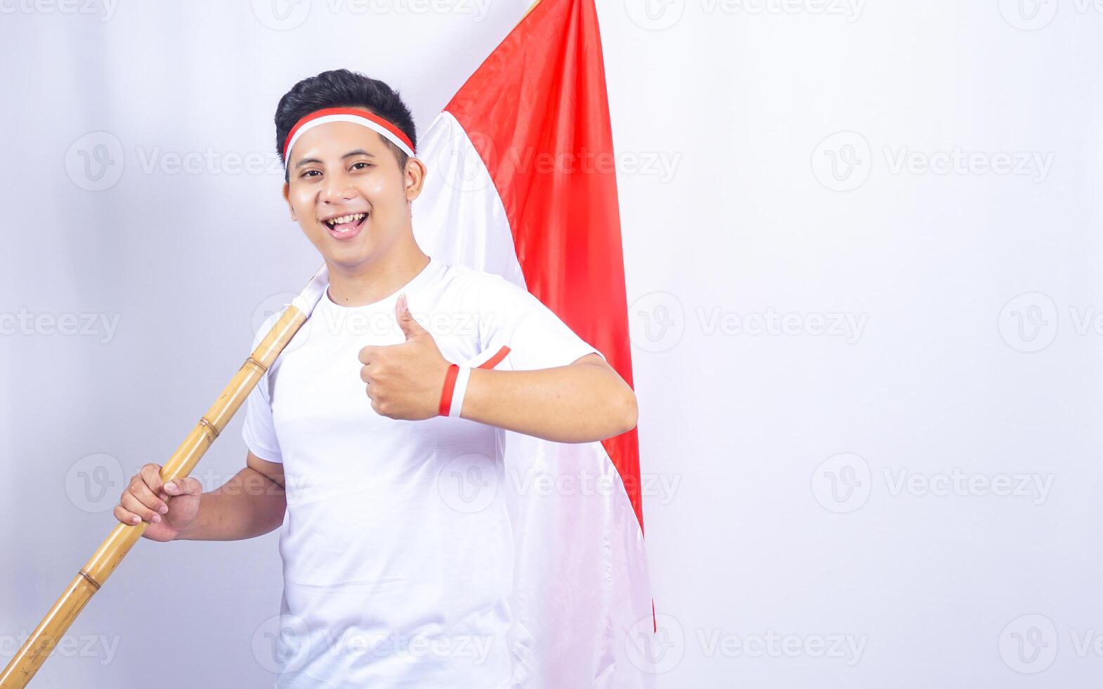 Handsome Indonesian Young Man Showing Thumbs up while Holding Country Flag photo