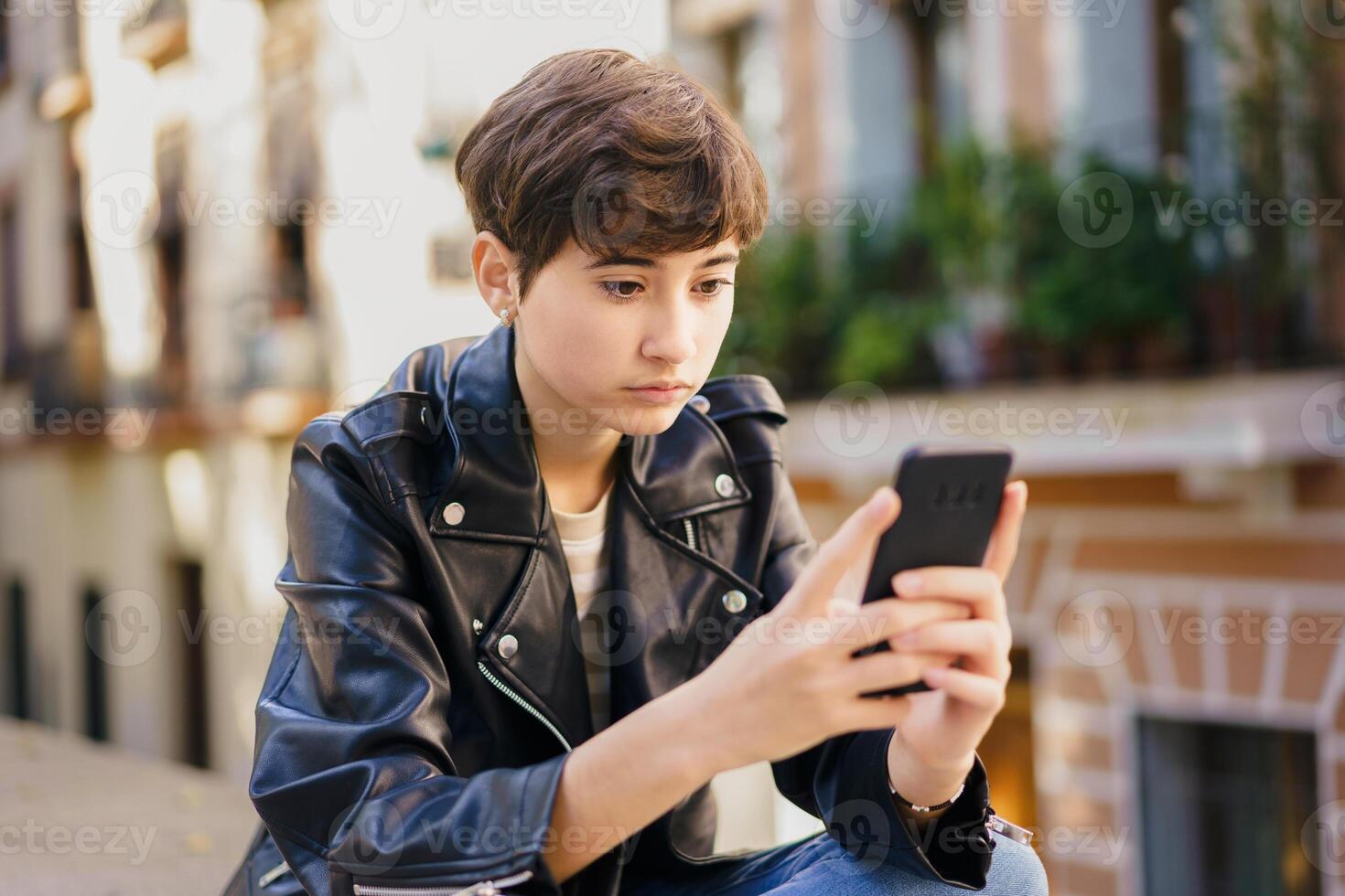 A teenage girl absorbed in her mobile phone in a vibrant urban setting, candidly captured photo