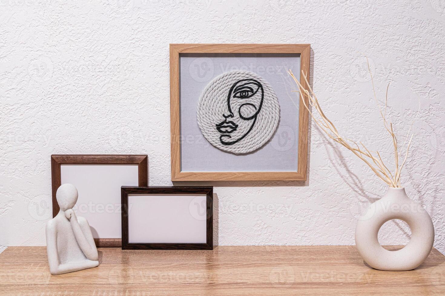 design elements of a modern room. stylish ceramic vases with dried flowers, photo frames, a framed painting on a white textured wall. Front view.