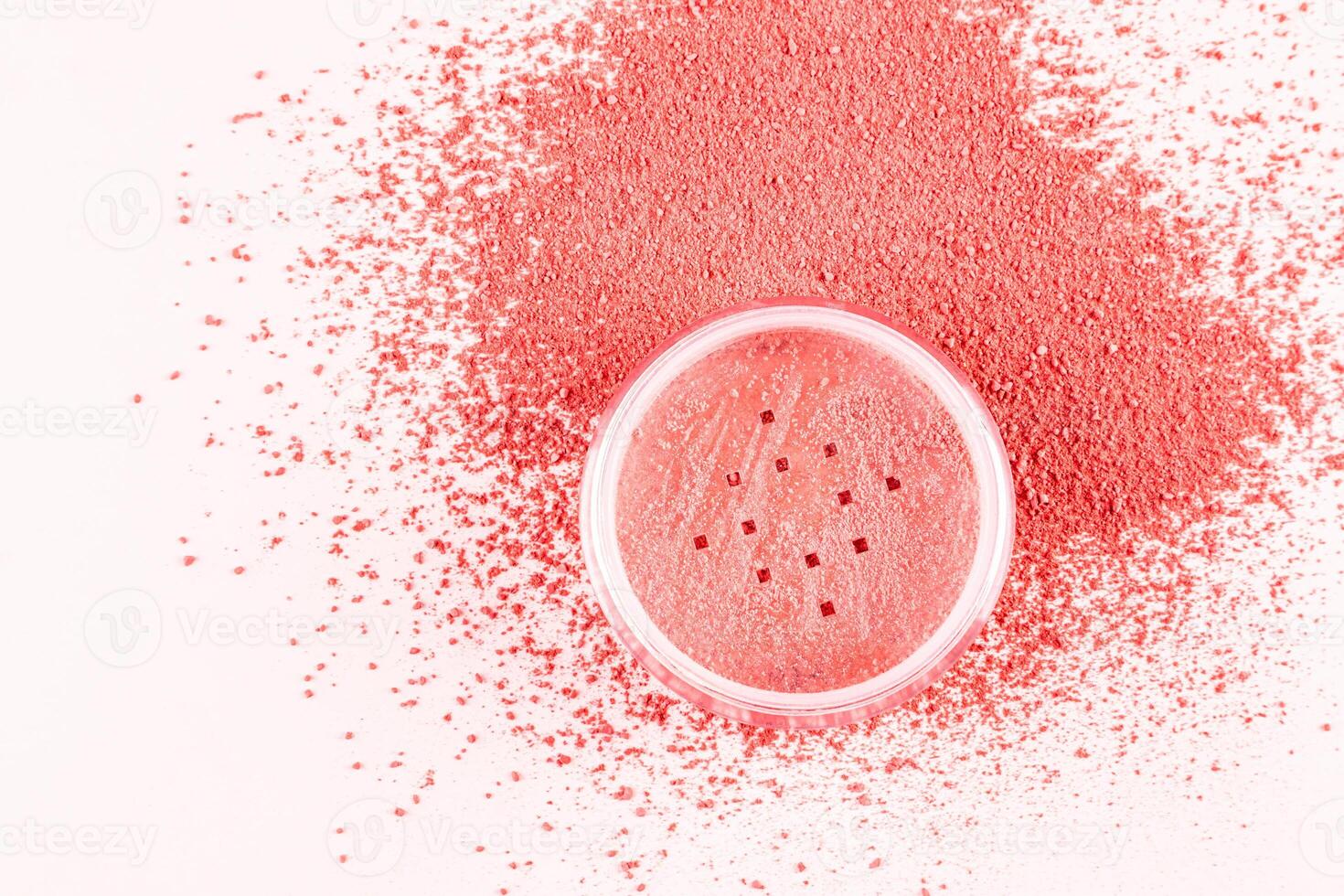 An open transparent cosmetic jar of pink-tone dry blush stands on a loose pink blush swatch. white background. A copy space. texture sample photo