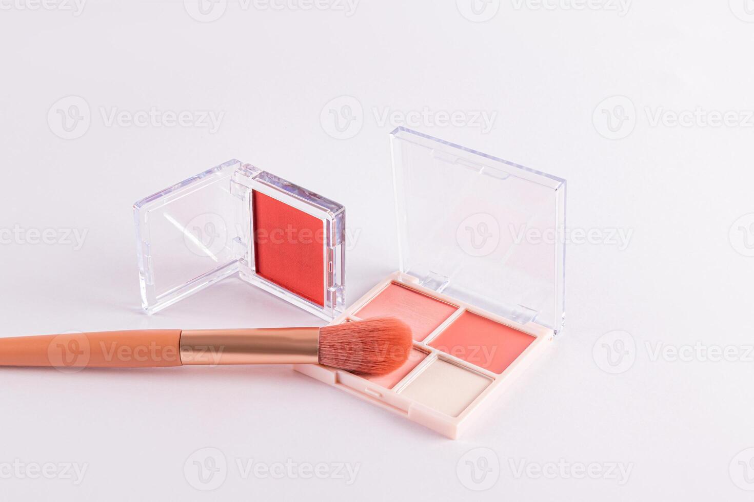 Two open packs with peach-tone blush and various light tones on a white background with professional makeup brush. space for text. concept cosmetics. photo