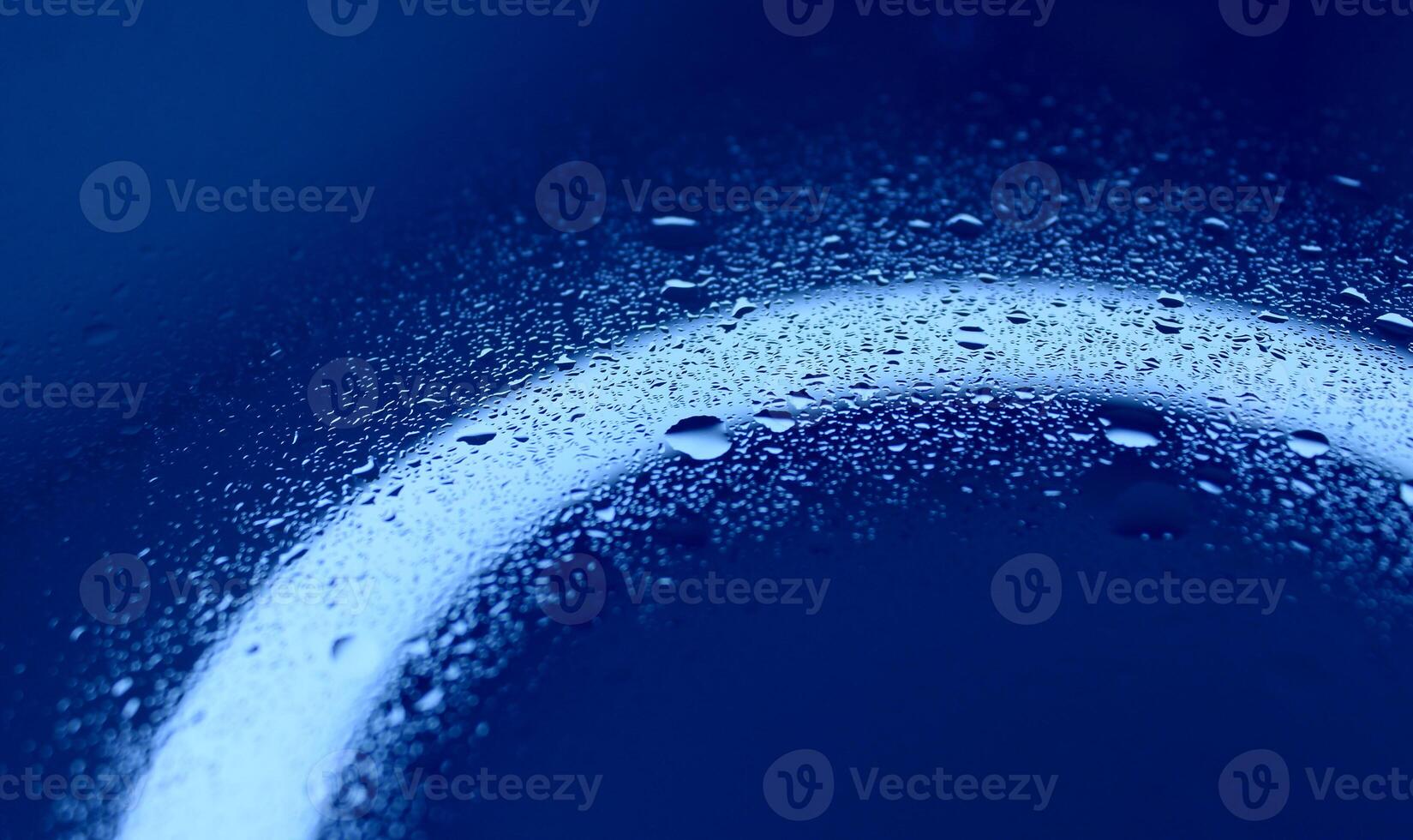 Texture of splashed water on illuminated blue glass surface photo