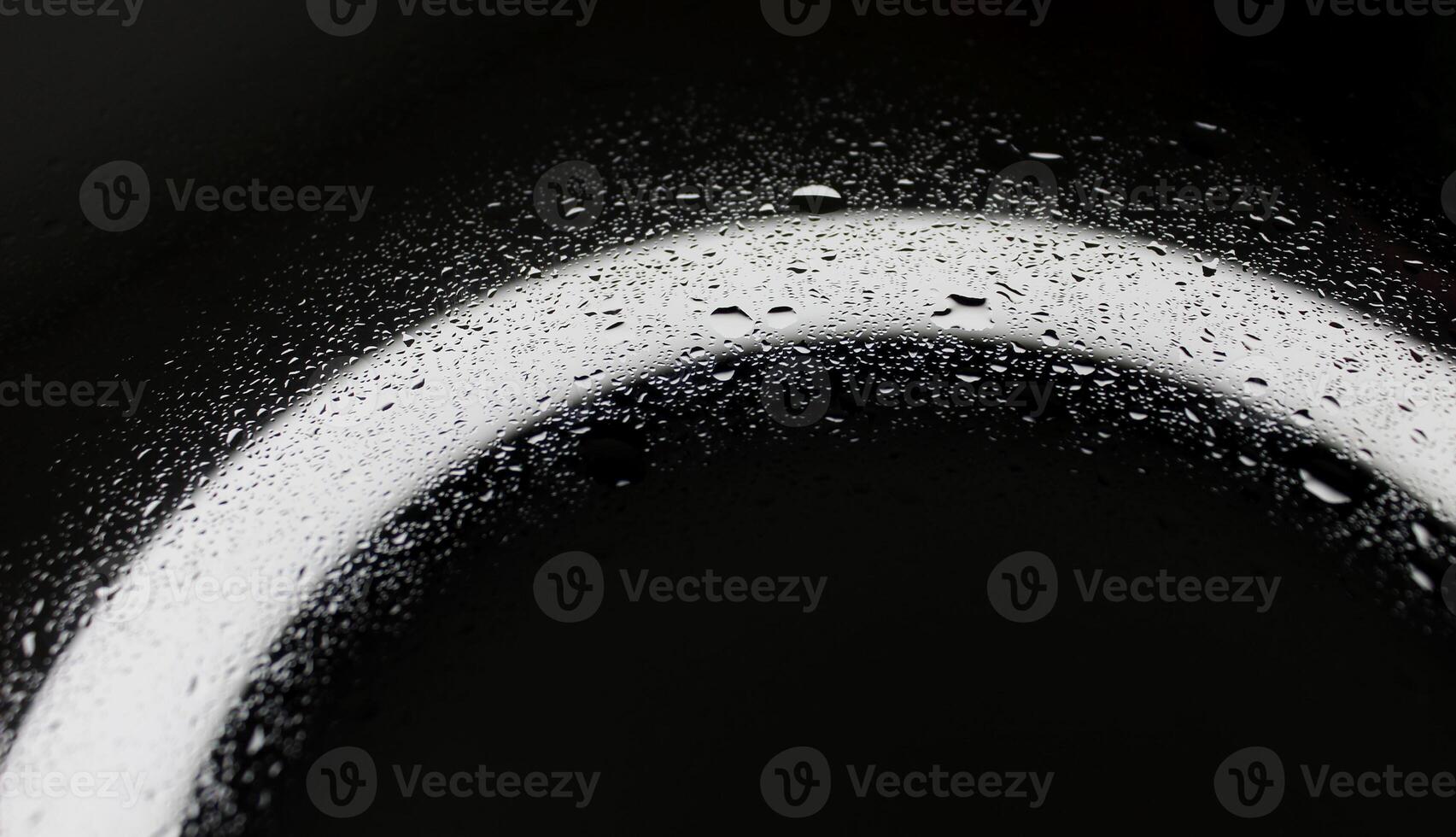 Small and large drops of water on a glass surface illuminated from below closeup view photo