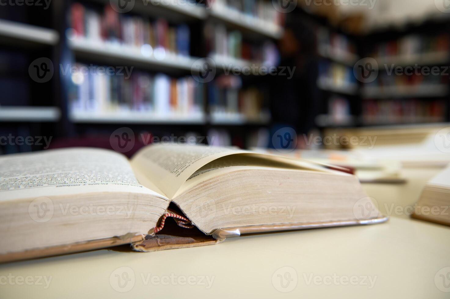 Open Book in Library With Shelves Blurred in Background photo
