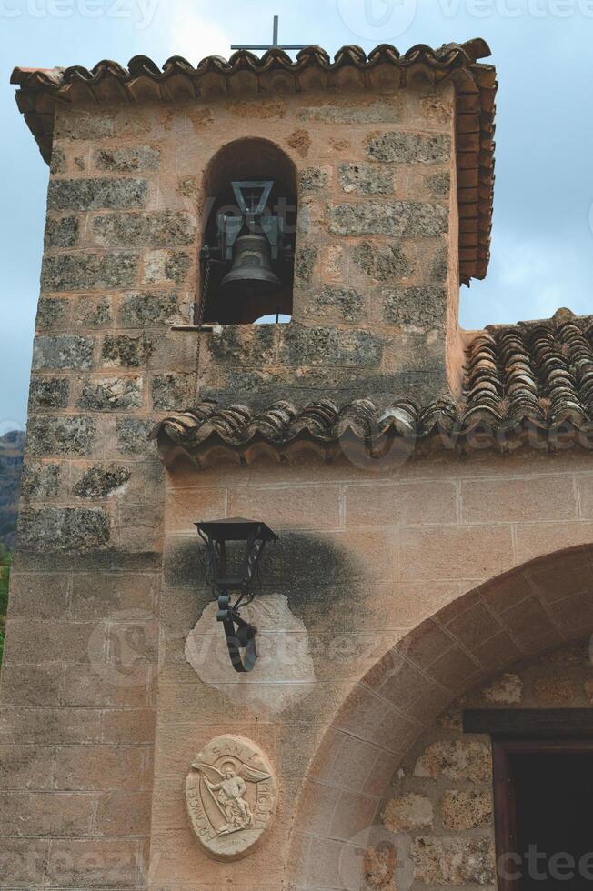 Stone church bell tower and decorative details under a cloudy sky photo