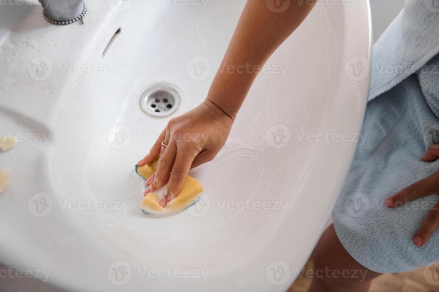 Hand Cleaning a Ceramic Sink Basin with a Sponge at Home photo