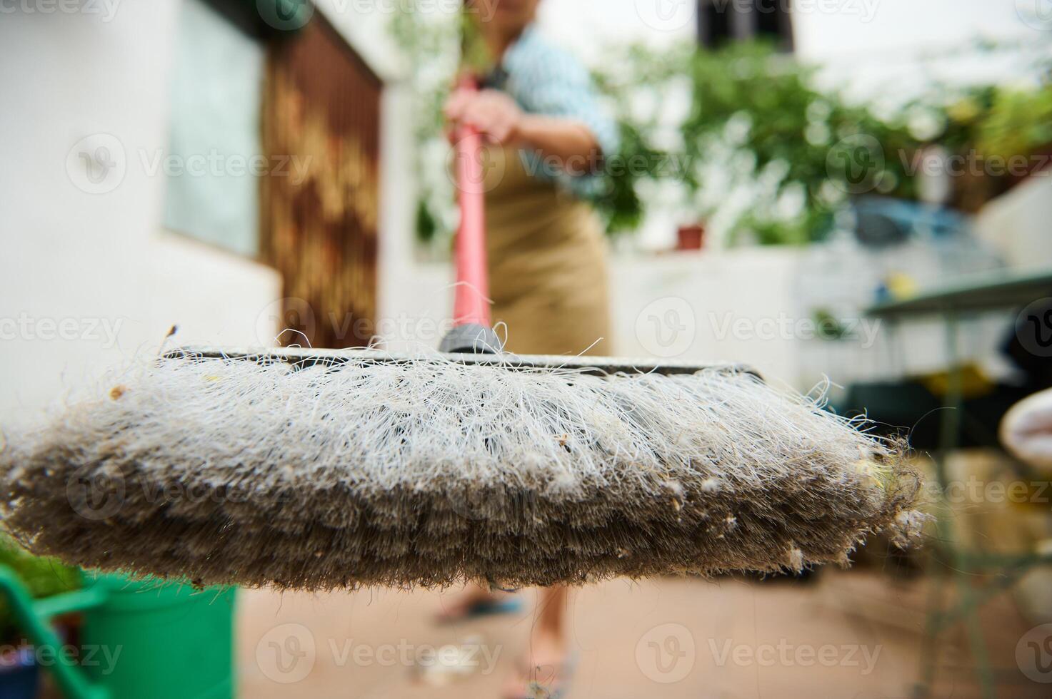 Focused shot of sweeping with dirt-covered broom in an outdoor setting photo