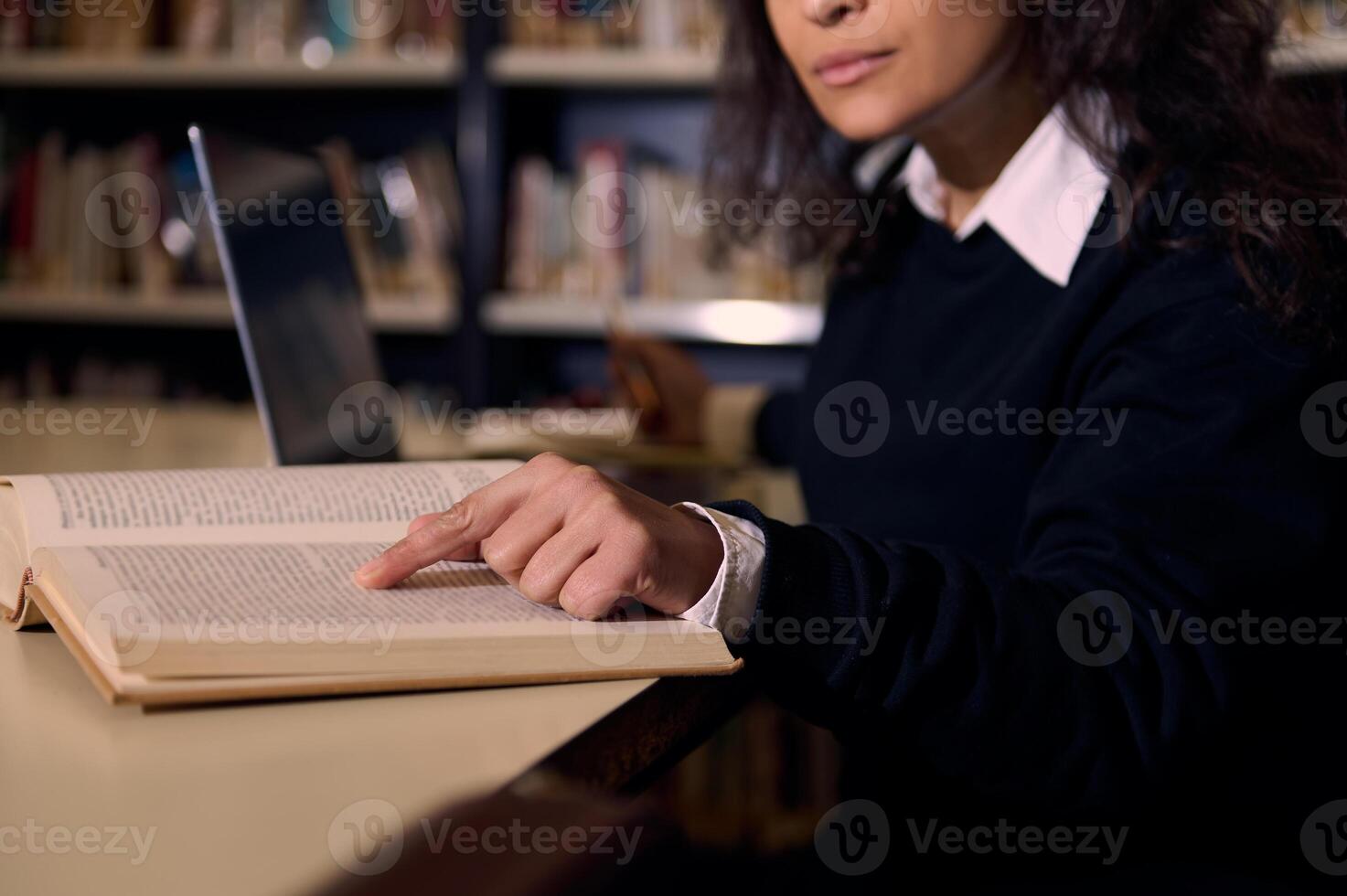 A person reading and pointing to a book in a library setting photo
