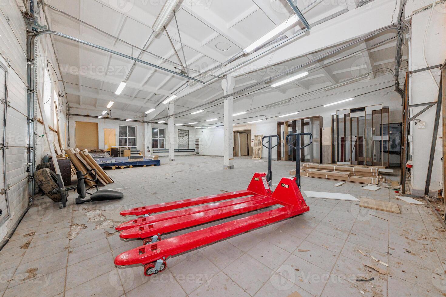 Silent Giants of Industry A Vast Warehouse Repository with Red Pallet Jacks Awaiting Action photo