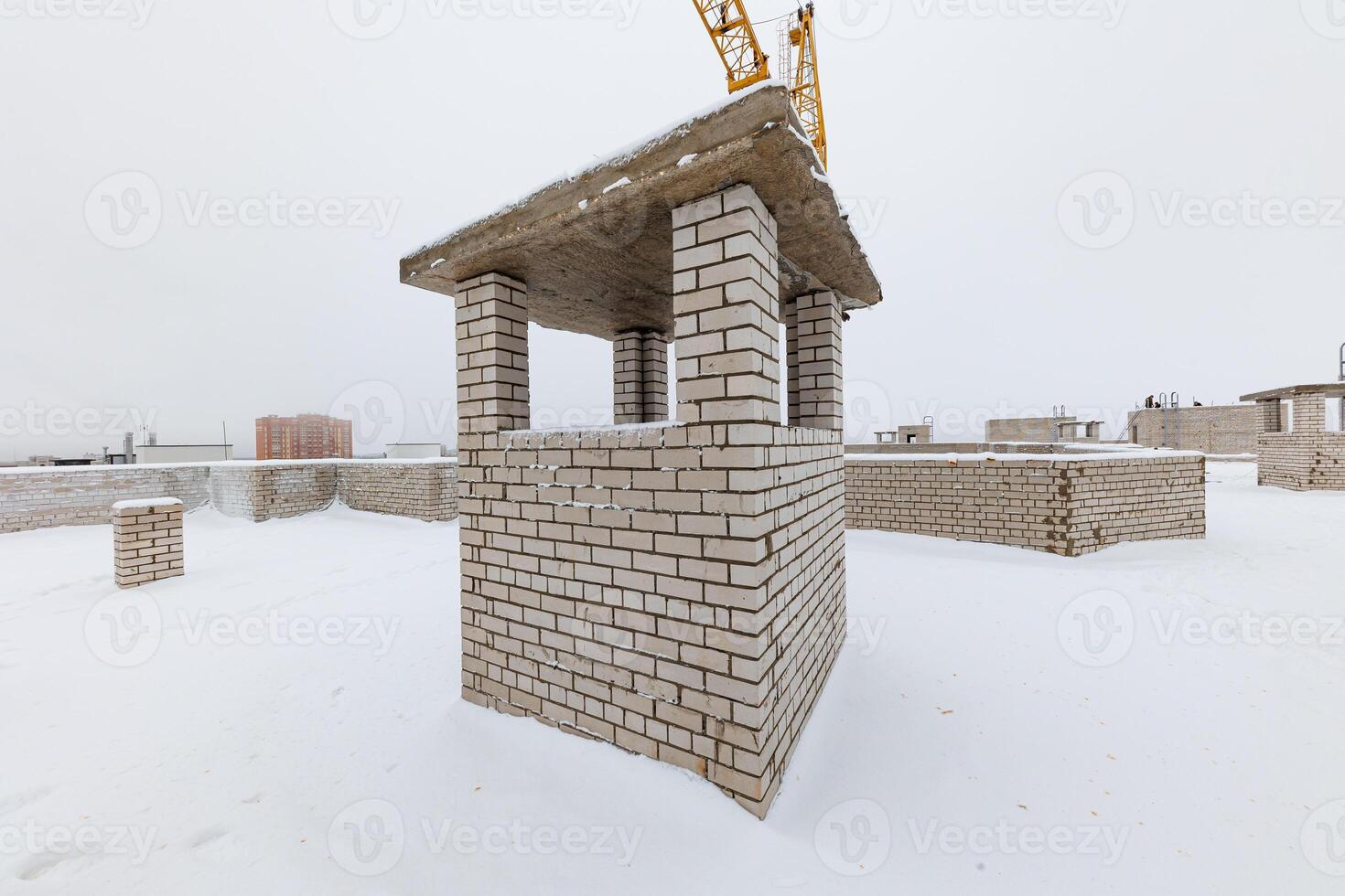 Silent Yet Rising A Snow-Covered Construction Site Embraces Winters Chill as a Crane Towers Over Brick Foundations. photo
