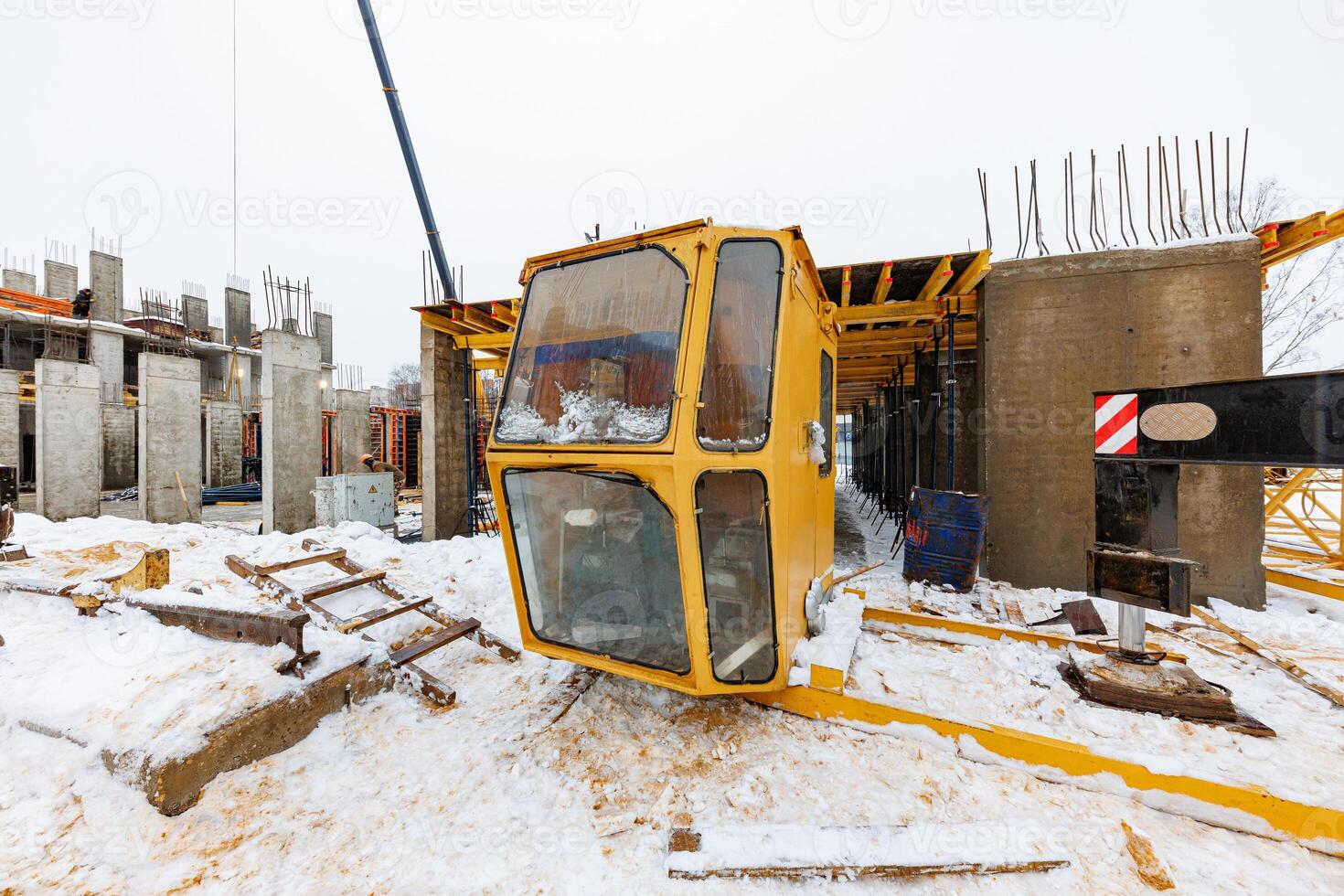 Abandoned Ambition A Snow-Covered Crane Cab Lies Forgotten Amidst Half-Built Concrete Dreams photo